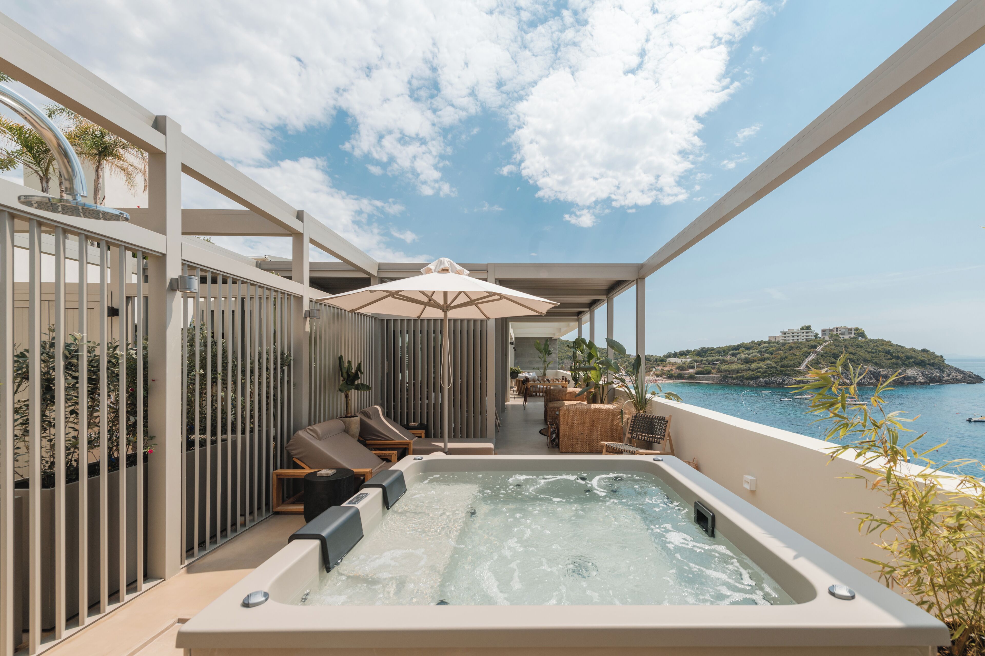 Un jacuzzi en un balcón con vistas al mar y una isla distante.
