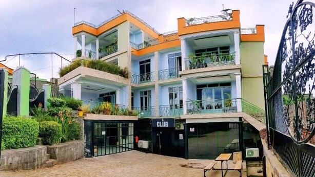 A multi-story building with balconies, a gated entrance, and outdoor seating. - ibizza resort (Shingiro)
