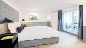 Een moderne hotelkamer met een groot bed, een nachtkastje met een lamp, een ingelijst schilderij aan de muur en een balkon met uitzicht.