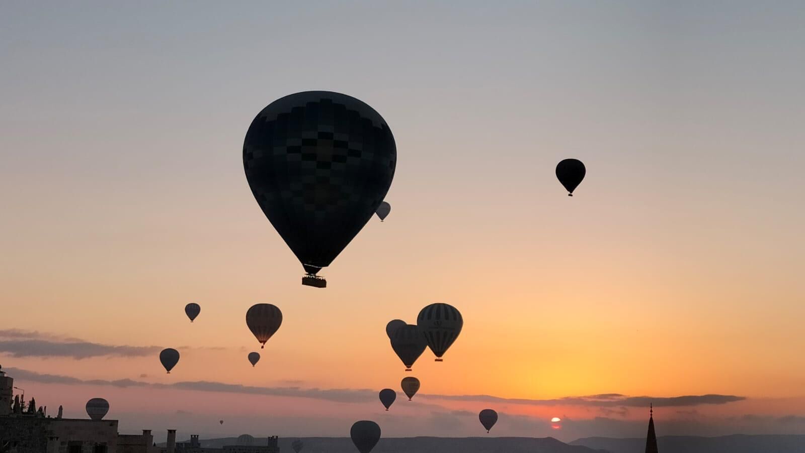 A sunset with multiple hot air balloons in the sky.