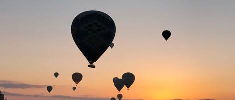 A sunset with multiple hot air balloons in the sky.