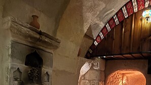 A cozy room with a stone fireplace, a wooden ceiling, and a patterned rug. - La Vie Cappadocia Cave Hotel (Nevsehir)