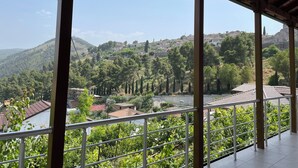 A balcony with a view of a hillside with houses and trees.