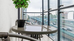 A balcony with a glass table, a potted plant, and a wicker chair. - RentPlanet - Bliska Wola (Warsaw)