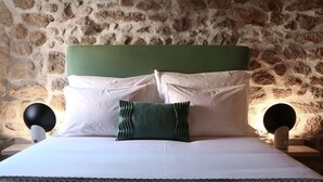 Una cama con cabecera verde, almohadas blancas y verdes, y una colcha verde con textura.