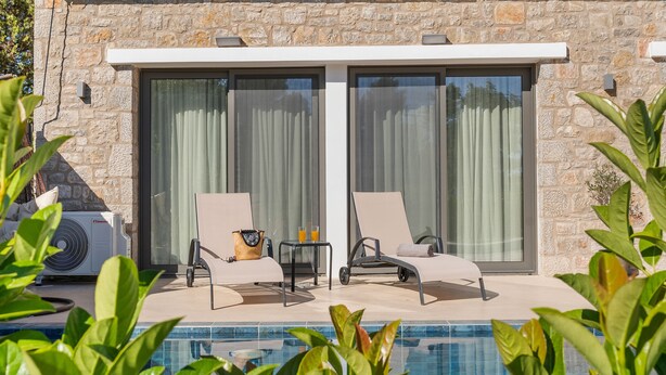 Un espace aménagé au bord de la piscine, comprenant deux chaises longues, une table avec des boissons et un appareil de climatisation.