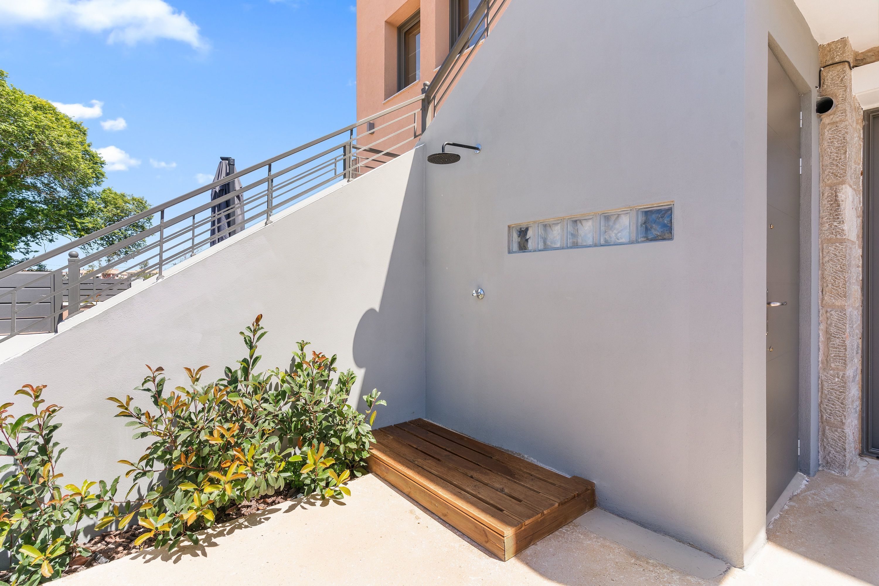 A modern building with a staircase, a small wooden bench, and a wall-mounted light fixture.