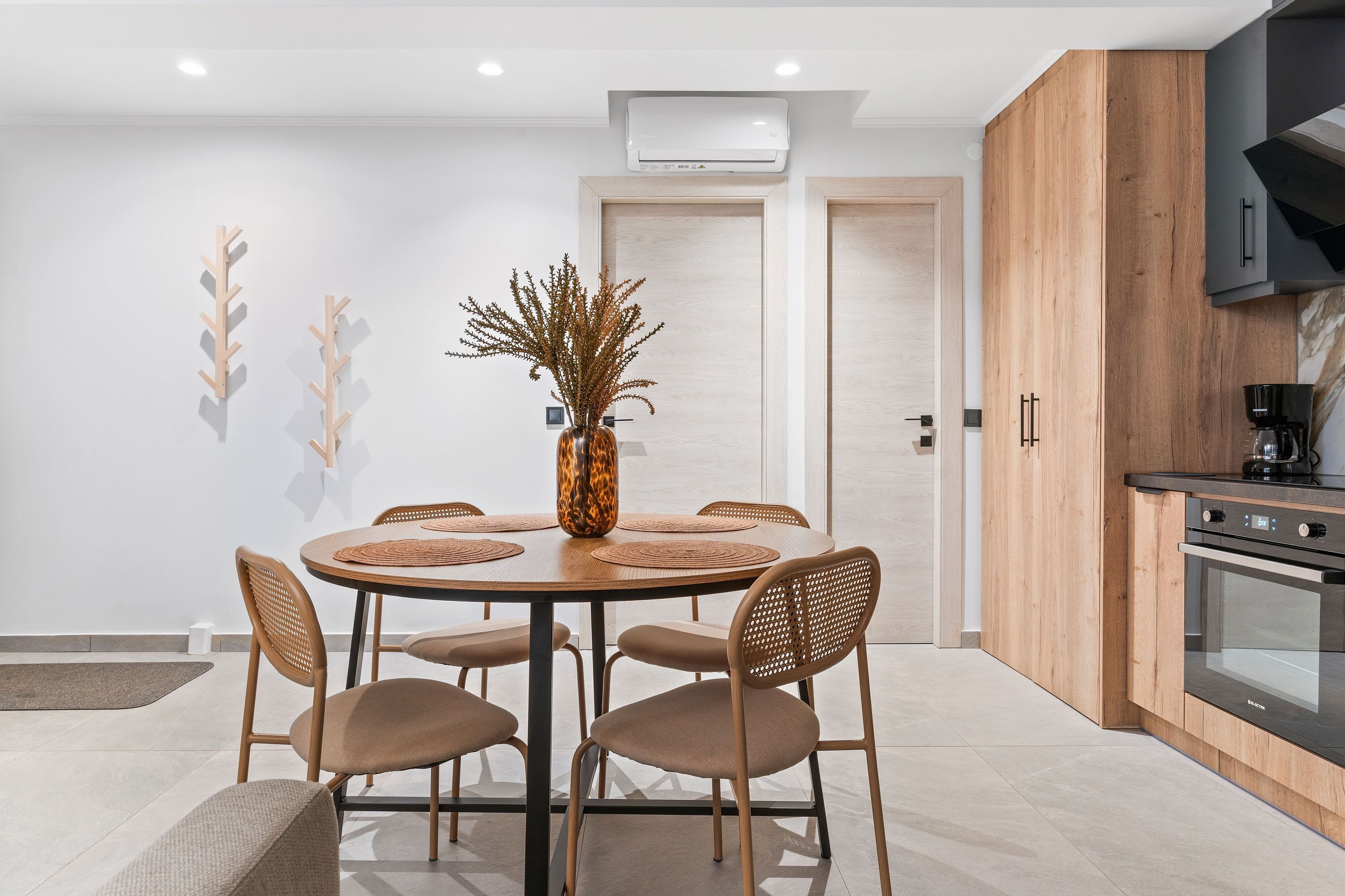 A modern kitchen with a round dining table, six chairs, and a coffee machine.
