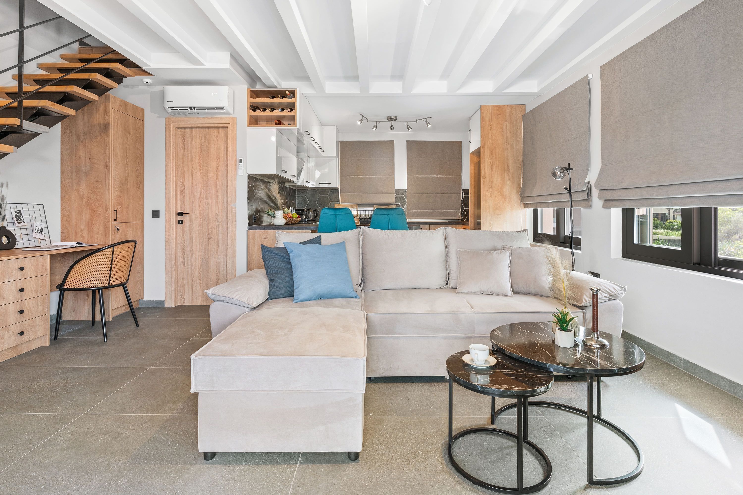 A modern living room with a sofa, a coffee table, and a dining area with a kitchen in the background.