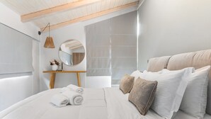 Un lit bien fait, avec des serviettes pliées, une table de chevet avec un miroir et un luminaire suspendu.