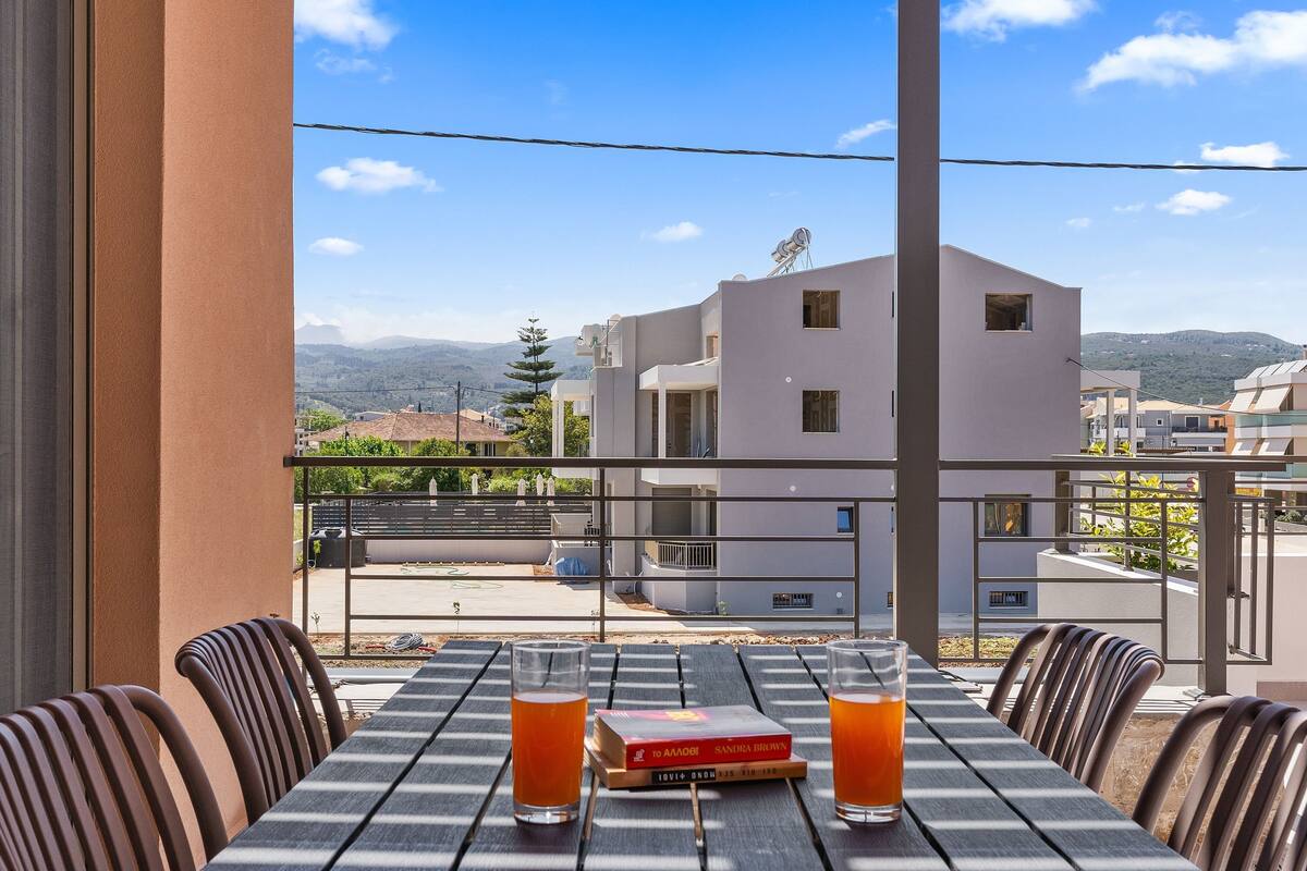 A balcony with a table set for two, two glasses of orange beverage, and a book titled "To Aardvark".