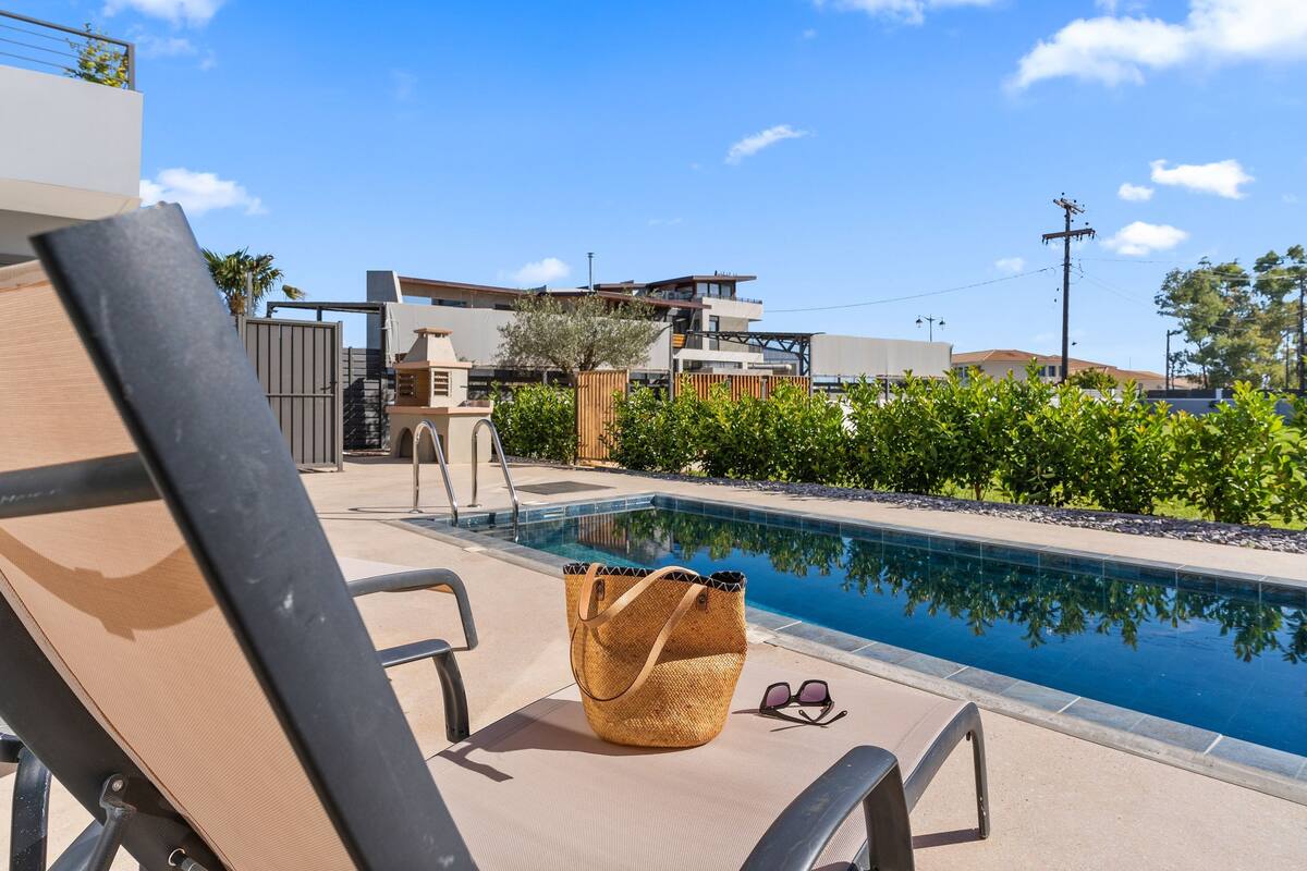 A poolside area with a lounge chair, a woven bag, and a pair of sunglasses.