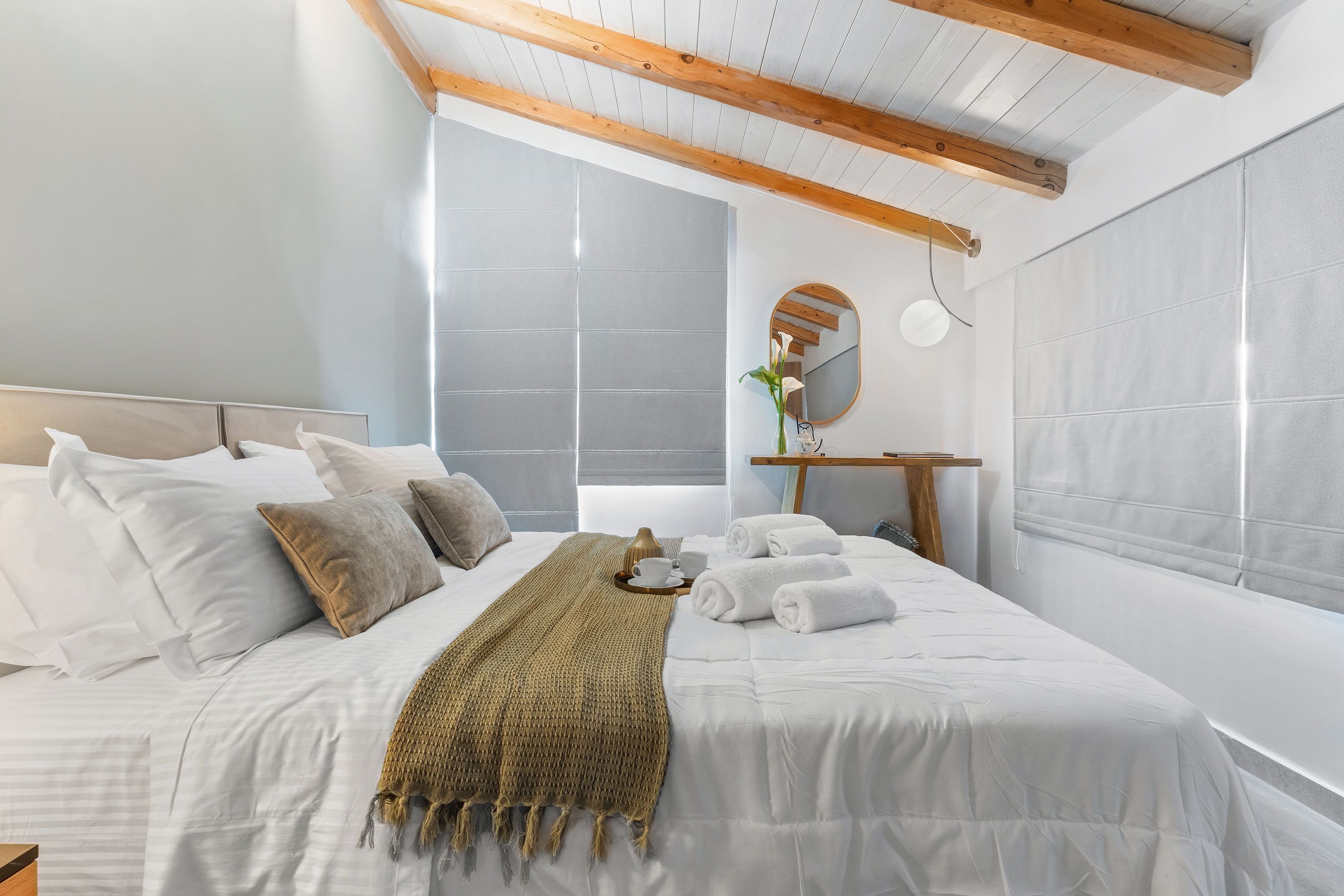 A modern bedroom with a large bed, a wooden ceiling, and a view of the outside.