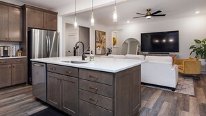 Een moderne keuken met een groot eiland, roestvrijstalen apparatuur en een flatscreen televisie.