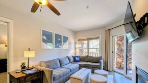A living room with a sectional sofa, ottoman, lamp, and artwork on the wall. - Summer Fun+ Mountain & River Views, Bike Path (Keystone)