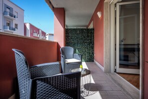 A balcony with wicker furniture and a glass door leading to a room. - Fior Di Loto Central (Cagliari)