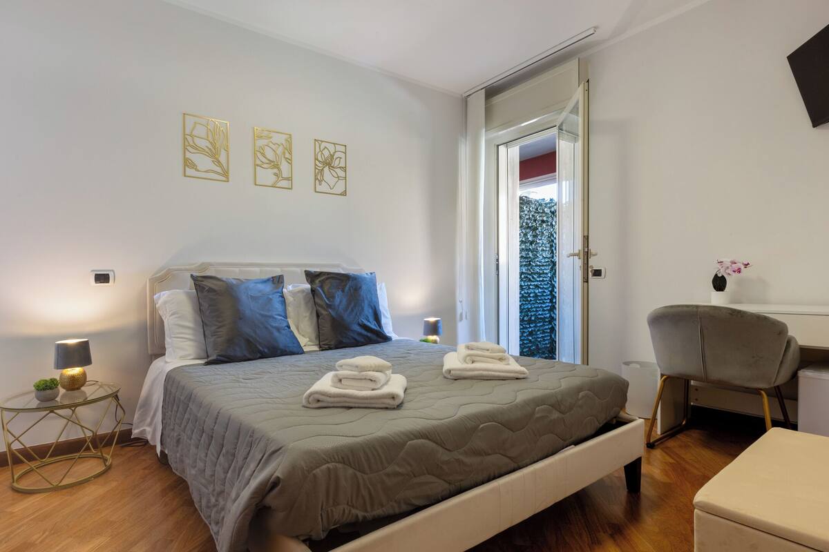 A bedroom with a bed, bedside tables, a chair, and a desk.