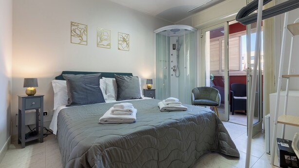 Un dormitorio con cama, lámparas de noche, ducha y una silla.