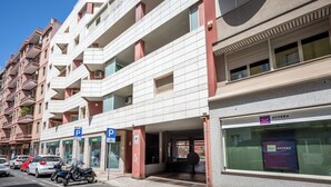Un edificio residencial de varios pisos con balcones, un estacionamiento y una tienda con el letrero AVVERA.