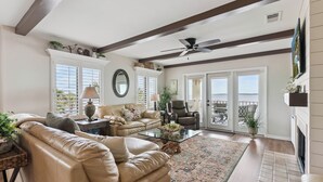 A spacious living room with a leather sofa, a glass coffee table, and a fireplace. - Ocean Front Paradise, Fantastic Views! sleeps 4 (St Simons Island)