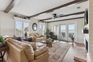 A spacious living room with a leather sofa, a glass coffee table, and a fireplace.