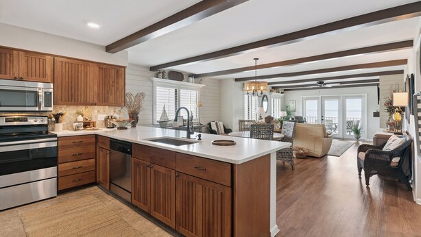 A spacious kitchen with wooden cabinets, a central island, and a dining area with wicker furniture. - Ocean Front Paradise, Fantastic Views! sleeps 4 (St Simons Island)