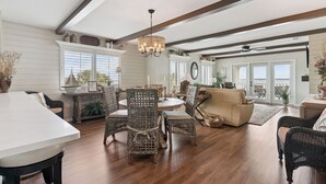 A spacious living area with a dining table, wicker chairs, a sofa, and a chandelier. - Ocean Front Paradise, Fantastic Views! sleeps 4 (St Simons Island)