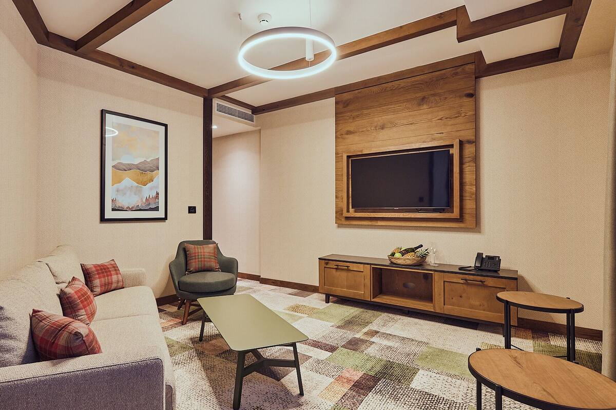 Un salon moderne avec un canapé, un fauteuil, une table basse et un téléviseur.