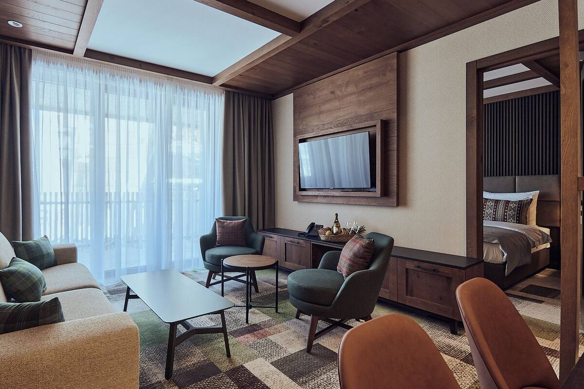 Une chambre d’hôtel moderne équipée d’un canapé, de fauteuils, d’une table basse, d’une télévision et d’un lit.