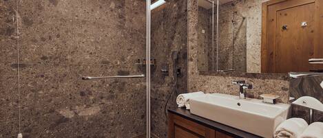A modern bathroom with a glass-enclosed shower, a sink with a mirror, and wooden cabinets.