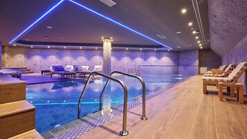 Una piscina techada, sillones reclinables de piscina