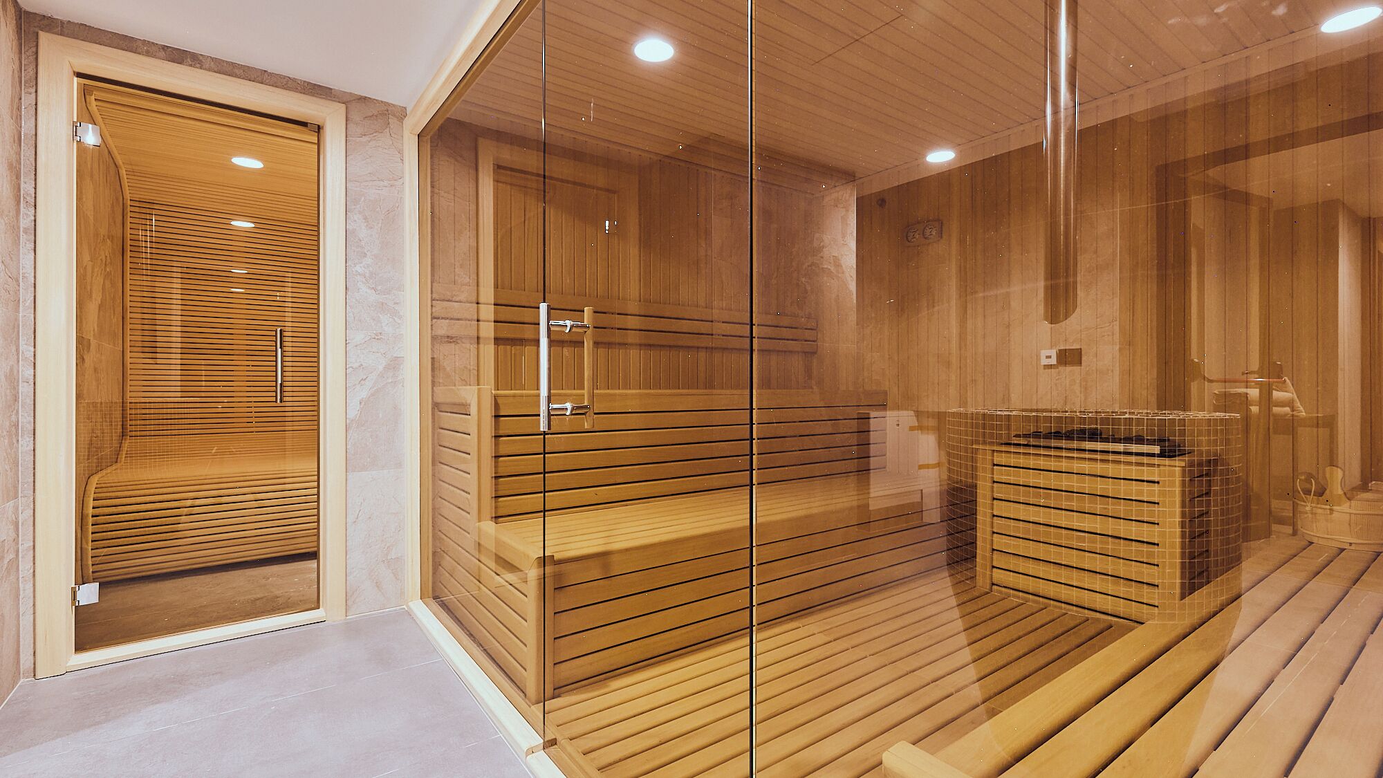 Un sauna avec des bancs en bois et une paroi en verre.