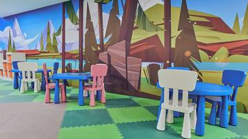 Children can play and explore in this vibrant play area with a colorful mural and comfortable seating.