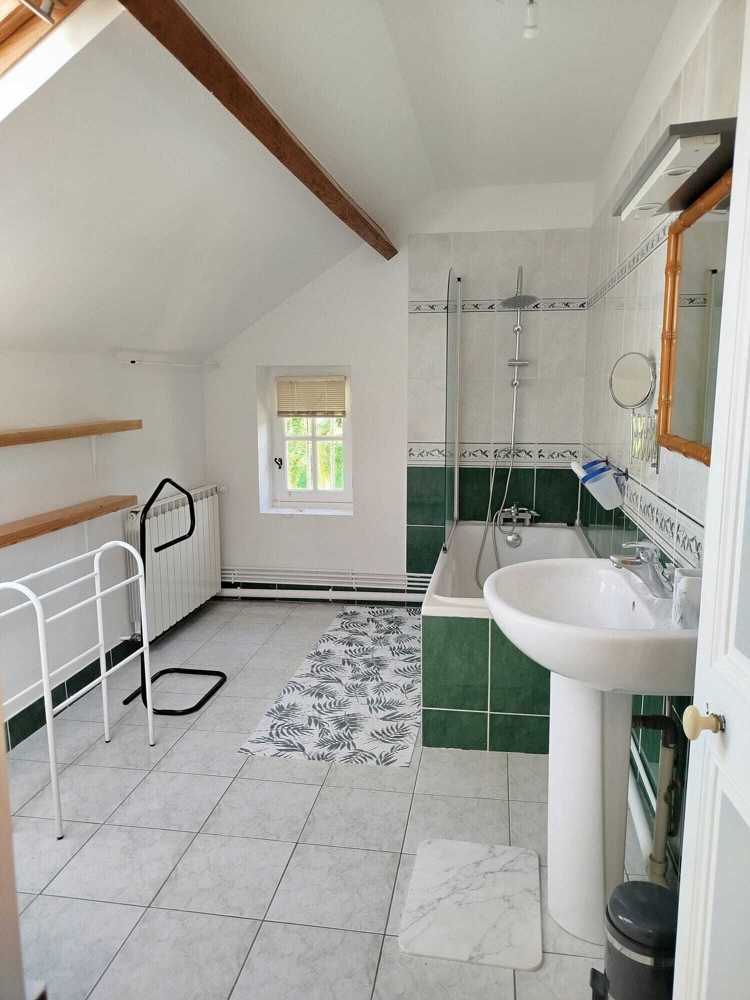 Un baño con bañera, lavamanos, ventana y radiador.