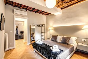 A bedroom with a bed, bedside tables, a mirror, and a ceiling with exposed beams. - Amazing Location, One Short Block From The Main Street In Trevi Fountain (Roma)