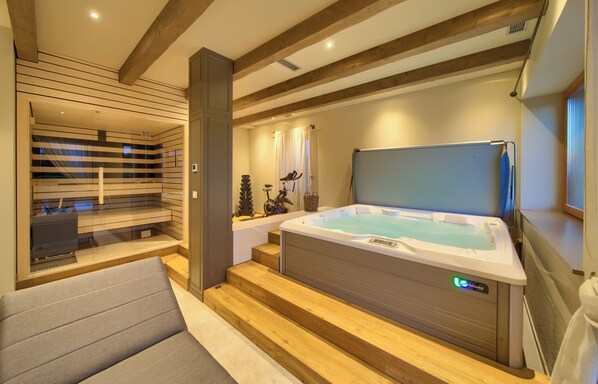 Een moderne badkamer met een bubbelbad, houten balken en een douchecabine van glas.