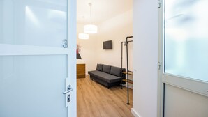 A modern room with a grey sofa, a wooden floor, and a white door. - Lioy 25 by Napoliapartments (Naples)