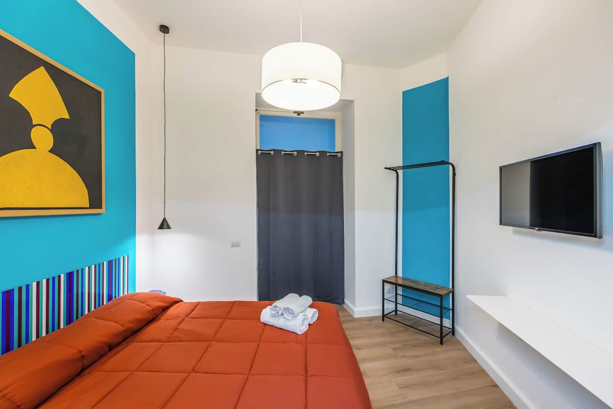 A modern hotel room with a large bed, a flat-screen TV, and a painting on the wall.