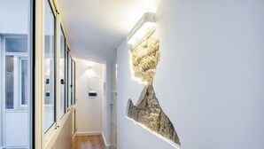 A hallway with a stone wall feature and a door at the end. - Lioy 25 by Napoliapartments (Naples)
