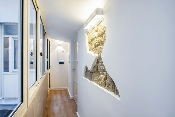 A hallway with a stone wall feature and a door at the end.