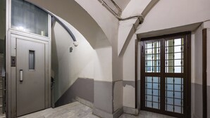 A hallway with a marble floor, a door with a glass panel, and a wall-mounted light fixture. - Lioy 25 by Napoliapartments (Naples)
