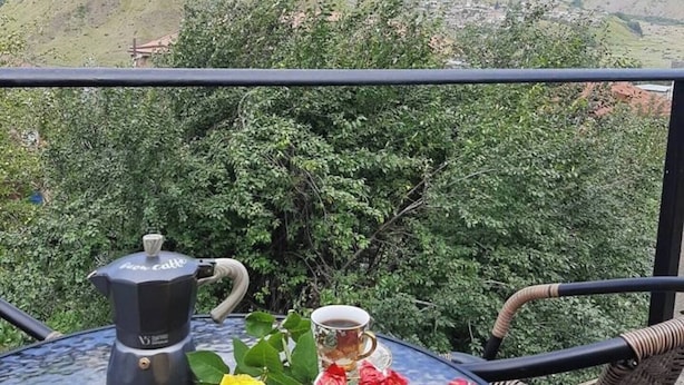 A table with a coffee pot and a cup, surrounded by greenery and a mountain view. - Royal Galaxy

 (Stepantsminda)