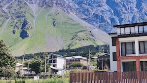 A mountain landscape with a residential area in the foreground, featuring modern buildings with balconies and a wooden fence. - Royal Galaxy

 (Stepantsminda)