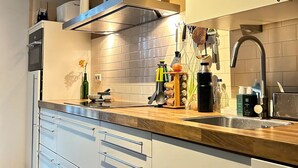 A modern kitchen with a built-in oven, a stainless steel sink, and a range hood. - A minute to the tram, a minute to the beach-explore Amsterdam like never before (Amsterdam)