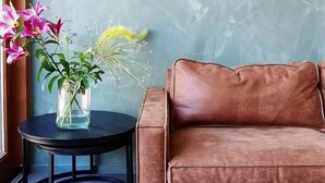 A brown sofa and a small round table with a vase of flowers. - A minute to the tram, a minute to the beach-explore Amsterdam like never before (Amsterdam)