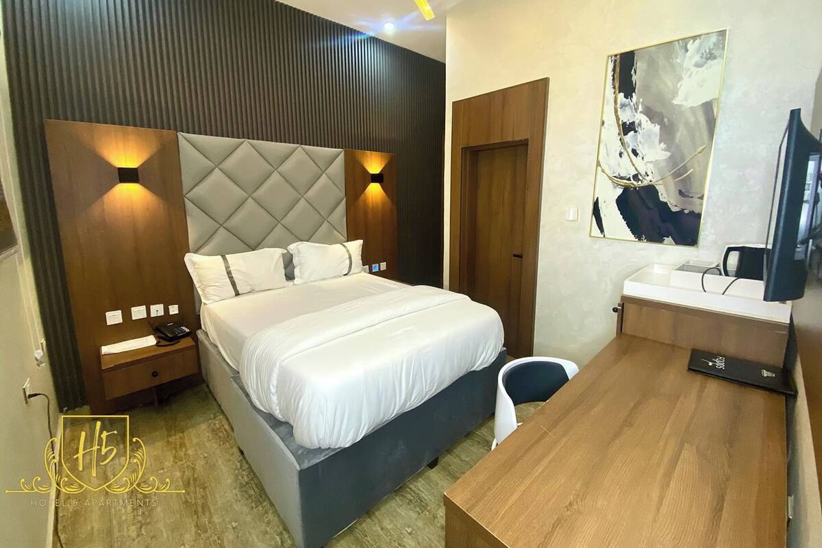 A modern hotel room with a large bed, bedside tables, a desk, and a television.