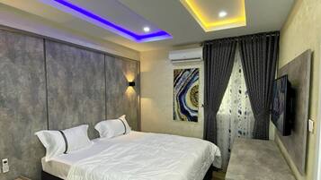 A modern bedroom with a bed, bedside tables, a TV, and a ceiling with LED lighting.