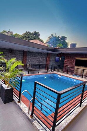 A rectangular swimming pool with a tiled edge, surrounded by a black metal fence.
