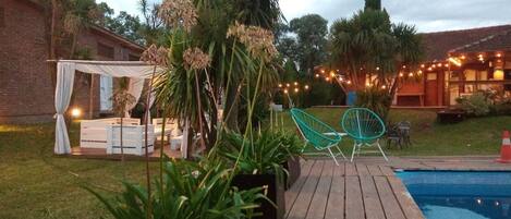 A backyard with a wooden deck, a pool, and outdoor seating.