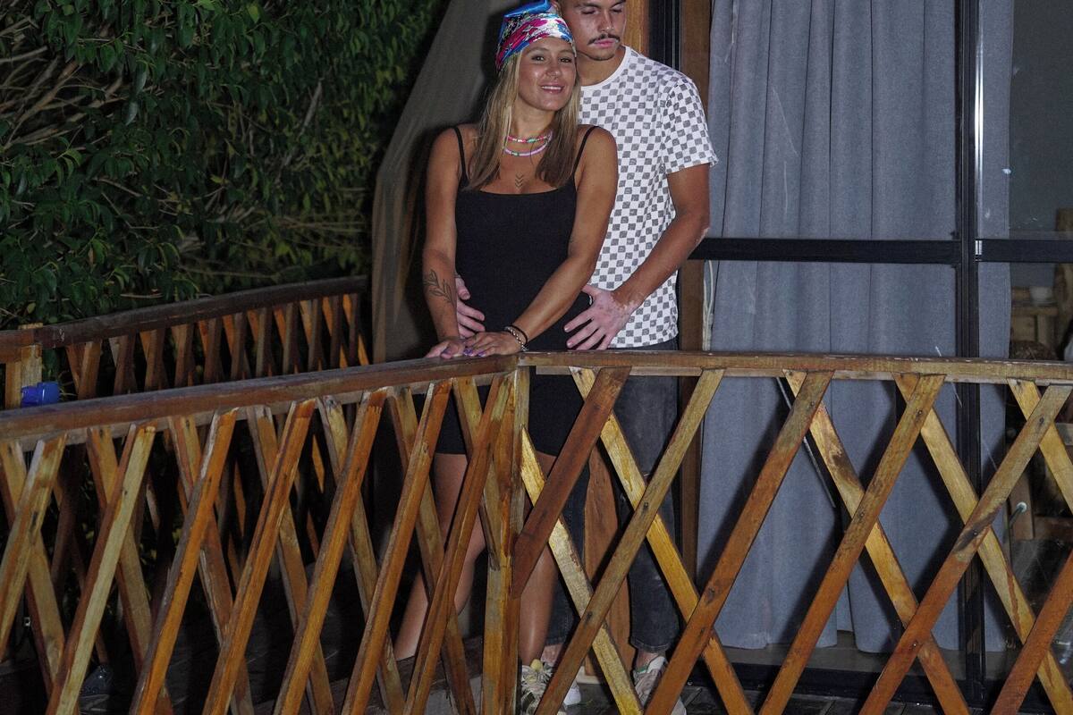 A couple standing on a wooden deck in front of a tent-like structure.